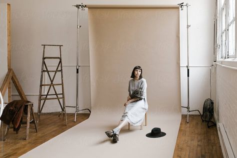 behind the scenes of model sitting in front of backdrop seamless paper in photo studio with props around by Nicole Mason for Stocksy United Photography Paper Backdrops, Seamless Backdrop Photography, Seamless Backdrop Photoshoot, Paper Backdrop Ideas, Paper Backdrop Photography, Seamless Paper Photography, Photoshoot Diy, Backdrop Photoshoot, Model Sitting