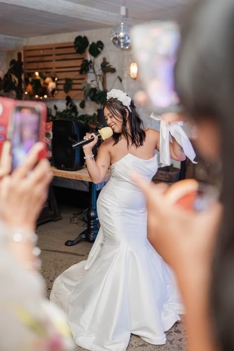 Bride wearing a strapless mermaid wedding dress with a flower headband holding microphone for karaoke wedding reception entertainment | wedding karaoke | wedding entertainment ideas | wedding games and fun | Lucie Watson Photography Karaoke Wedding Reception, Wedding Games Outdoor, Wedding Karaoke, Karaoke Wedding, Strapless Mermaid Wedding Dress, Holding Microphone, Wedding Entertainment Ideas, Wedding Reception Entertainment, Reception Entertainment