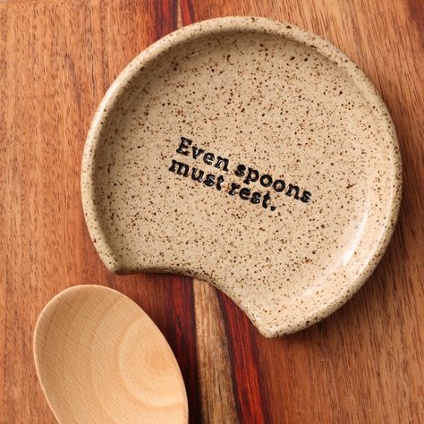 Speckled ceramic spoon rest with the phrase Even Spoons Must Rest imprinted onto it. Spoon Rest Sayings, Ceramic Spoon Rest Painting Ideas, Pottery Spoon Holder, Easy Pottery Projects, Ceramic Spoon Holder, Air Dry Clay Spoon Rest, Diy Spoon Rest, Spoon Rest Ideas, Spoon Rest Diy