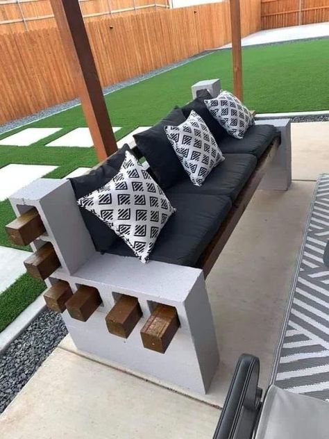 Cinder Block Bench1 Outdoor cinder block bench with wooden planks, black cushions, and patterned throw pillows on a patio with artificial grass. | Sky Rye Design Concrete Block Bench, Cinder Block Diy, Outdoor Bench Ideas, House Outside Decor, Block Bench Ideas, Backyard Pallet Ideas, Cinder Blocks Diy, Cinder Block Furniture, Cinder Block Bench