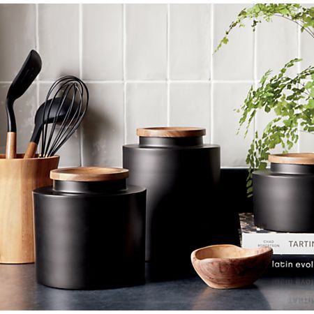 Clark Large Matte Black Canister + Reviews | Crate and Barrel Black And Wooden Kitchen Accessories, Simple Kitchen Accessories, Kitchen Counter Containers, Black Canisters For Kitchen, Black And Wood Kitchen Decor, Kitchen Decor Inspiration Modern, White And Black Kitchen Decor, Black Kitchenware, Black And Tan Kitchen