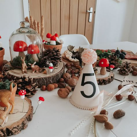 Woodland birthday set up display on a white table. Using pine cones, log cuts, moss, glass dome and toy woodland animals Woodland Birthday Decor, First Birthday Outdoor Theme, Fairy Forest Birthday Party, Forest Animals Birthday Party, Mushroom Party Theme, Enchanted Woodland Party, Fairy Woodland Party, Toadstool Birthday Party, Mushroom Balloon Arch