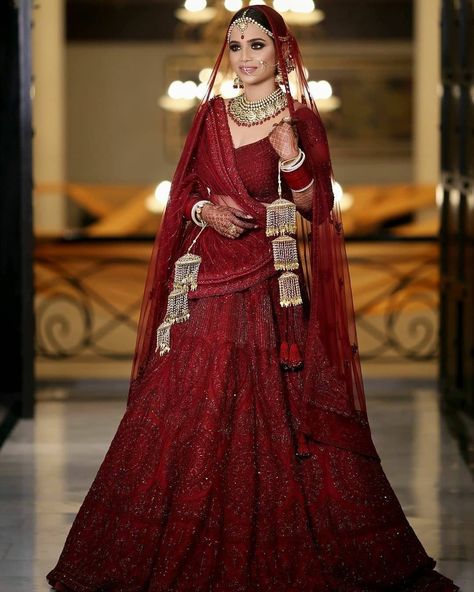 It’s a timeless piece that just never goes out of style. Jewelry With Red Lehenga, Bride In Maroon Lehenga, Maroon Bridal Lehenga Pakistani, Maroon Chooda Designs Brides, Lehnga Designs 2023, Maroon Lengha, 2023 Lehenga, Maroon Bridal Lehenga, Red Bridal Lehenga