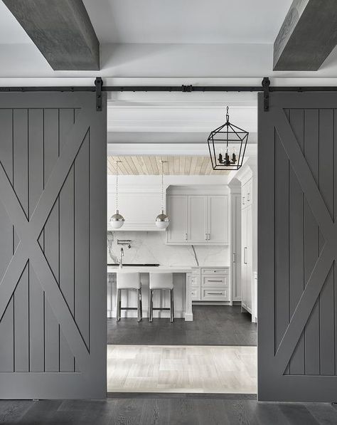 Gray plank barn doors on rails enclose a cottage kitchen with white cabinets, plank walls and dark stained oak wood floors. Barn Door Kitchen, Dark Stained Wood Floors, Sliding Door Ideas, Granny Flat Ideas, Barn Door Ideas, White Barn Door, Kitchen Transitional, Cottage Style Kitchen, 70s House