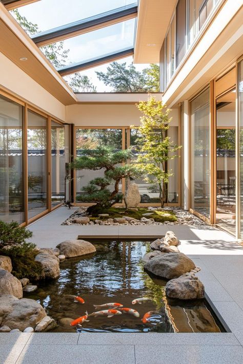 Modern japanese inner courtyard under a skylight roof with koi pond rocks and bonsai trees the house has large windows and shoji screen doors. Check out all of these Japanese courtyard houses that blend nature, minimalism, and tranquility to embrace full zen living. Tree Through House, Japanese Garden Design With Koi Pond, Courtyard Roof Design, House With Trees Inside, Home With Interior Courtyard, Modern House Courtyard Design, Japanese Style Interior Design Modern, Courtyard Style Homes, Home With Pond