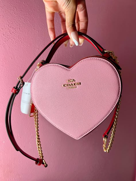 The Coach Heart Bag is the new it bag that recently dropped at the Coach Outlets. It's hard to find, but check out my blog to see how I was able to get one! Coach Bags Heart, Heart Coach Purse, Pink Coach Bag Aesthetic, Coach Valentine Bag, Coach Heart Bag Outfit, Heart Coach Bag, Coach Heart Purse, Coach Bag Pink, Pink Luxury Bag