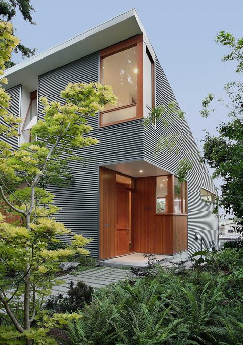 A modern house with corrugated metal siding and a wood front door and window frames. Home Siding Ideas Exterior, Corrugated Metal Ideas, Metal Siding House, A Frame Interior, Shed Architecture, Brown Landscape, Corrugated Metal Siding, Funny Real Estate Quotes, Corrugated Sheets