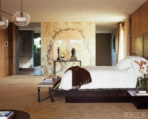 In the master bedroom of "Armageddon" director Michael Bay's home, a backlit wall of onyx partially conceals the bath, the walls are paneled in oak, and the custom-made bed is dressed in Frette linens; the headboard leather and Christian Liaigre console table and bench are from Holly Hunt, and the light fixtures and sconces are by Alison Berger. Tour the rest of the home here. Painted Wall Design, Wallpaper Wall Design, Accent Wall Design Ideas, Celebrity Bedrooms, Bedrooms Luxury, Accent Wall Design, Bedroom Accent Wall, Pallet Walls, Luxury Bedrooms