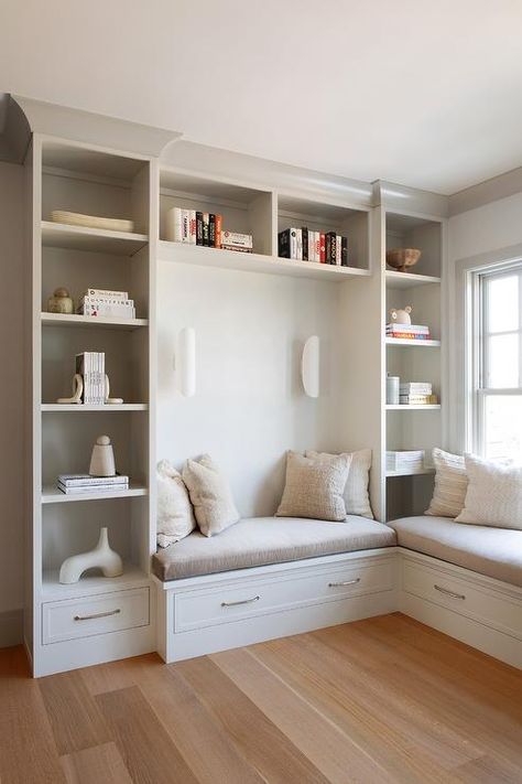 Light gray bookcases frame a light gray built-in bench topped with a gray cushion and adorned with polished nickel pulls. Dark Massage Room, Bookcase In Bedroom, Seating Nook, Chango & Co, Built In Bench Seating, Built In Window Seat, Boy's Rooms, Girl's Rooms, Room Nook