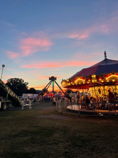 vertical photo of a sunset behind a lit up merry go round and other carnival rides Fair Aesthetic Fall, Small Town Carnival Aesthetic, Carnival Fair Aesthetic, Town Fair Aesthetic, Summer In A Small Town Aesthetic, Small Town Events, Rich Small Town Aesthetic, Small Town Activities, Small Town Festival Aesthetic