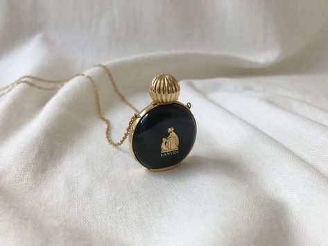 A beautiful, rare vintage Arpege by Lanvin miniature perfume bottle pendant with long chain necklace. The bottle is made of black glass with a metal screw-top, stenciled Lanvin logo on front of the bottle, embossed label on metal piece at bottom of bottle. No perfume inside.