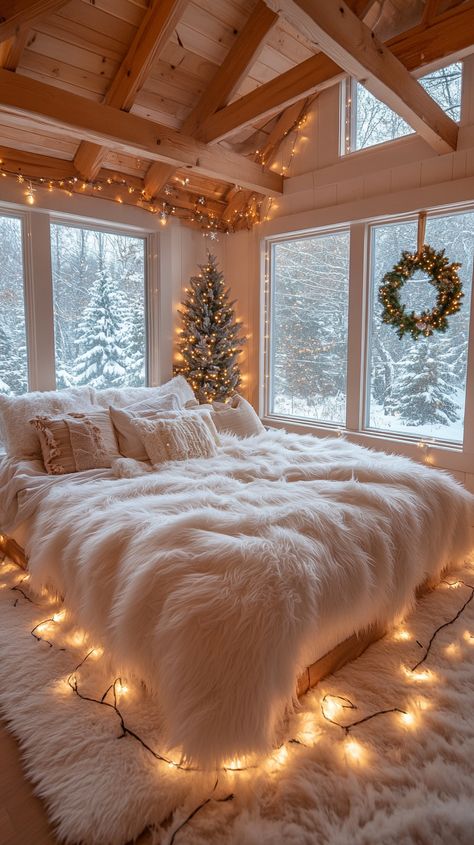 Cozy bedroom with white fur blankets, twinkling Christmas lights, a wreath, and snow-covered trees visible through large windows. Christmas Decor Astetic, Cozy Winter Aesthetic Christmas, Christmas Bedroom Simple, Christmas Cosy Aesthetic, Calm Christmas Aesthetic, Christmas Decorating Aesthetic, Winter Theme Bedroom, Christmas Master Room, Christmas Magic Aesthetic