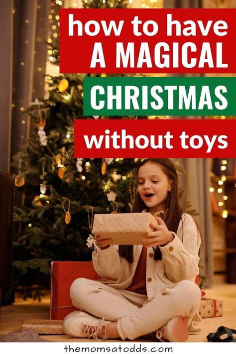 How to have a magical Christmas without toys. Photo of child sitting under Christmas tree with a gift. No Toy Christmas For Kids, Magical Christmas For Kids, Christmas Presents For Toddlers, Christmas Traditions Around The World, Make Christmas Magical, Christmas With Kids, Decorating A Christmas Tree, Non Toy Gifts, Traditions Around The World