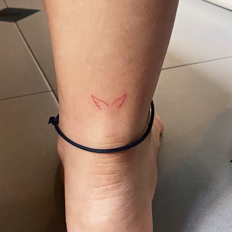 Minimalist red angel wing tattoo on your Achilles heel! Angel Wing On Ankle, Back Of The Heel Tattoo, Red Angel Wing Tattoo, Micro Ankle Tattoo, Dainty Red Ink Tattoos, Red Angel Wings Tattoo, Red Minimal Tattoo, Red Wing Tattoo, Fine Line Angel Wings