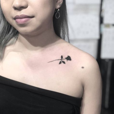 Black rose tattoo on the collarbone.