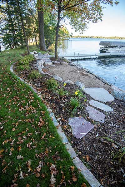 Let Backyard Reflections transform your lakeshore property into a relaxing outdoor oasis. We offer shoreline landscape services and more. Call us at (320) 274-6336. River Property Landscaping, Lake Beach Landscaping Ideas, River Beach Ideas, Lake Edge Landscaping, Lake Front Landscaping Ideas, Landscape Ideas For Lake House, Lakeside Beach Landscaping, Lake Property Landscaping, Lake Shoreline Landscaping