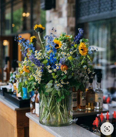 Yellow Blue Floral Arrangement, Sunflower Table Decoration, Sunflower With Blue Flowers, Delphinium Arrangement Vase, Blue Floral Table Arrangements, Blue And Yellow Flower Centerpieces, Blue And Yellow Summer Wedding, Wild Flower Arrangements Centerpieces, Blue Yellow Flower Arrangements