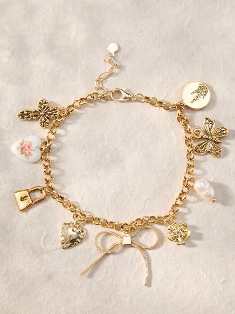 This bracelet features a bow charm with butterfly, cross, pearl, heart, lock, flower, and lilac accents, adding a touch of elegance to any outfit. Altered State Jewelry, Jewelry Charm Bracelets, Gold Charm Jewelry, Womens Gold Jewelry, Coquette Charm Bracelet, Pretty Jewellery Bracelets, Homemade Charm Bracelets, Aesthetic Charm Bracelet, Cute Gold Bracelets