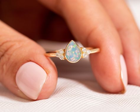 "Valentine Day Sale! 14k Gold Opal Engagement Ring/Pear Shaped Ring/Teardrop Opal Diamond Ring/Natural Ethiopian Opal/Promise Gift/Proposal ★ ★ ★ ★ CUSTOM/DUTY-FREE SHIPPING WORLDWIDE, BUYERS DON'T HAVE TO PAY ANY CUSTOM FEES WHILE IMPORTING ★ ★ ★ ★ Details Made to order Material: 14k/18k Gold Color Options: Yellow Gold, White Gold, Rose Gold, ★ Center Stone: Opal, Pear Size: 5 x 7 mm Approx Weight (Ct): 0.69 ★ Accent Stones: Diamond Round Size: 1.5 mm * 6 No.s Approx Weight (Ct): 0.084 ★ 100% N Engagement Ring Teardrop, Cluster Wedding Band, Gold Opal Engagement Ring, Opal Promise Ring, Ring Teardrop, Opal Diamond Ring, Pear Shaped Ring, Pear Shaped Engagement Rings, Moonstone Engagement