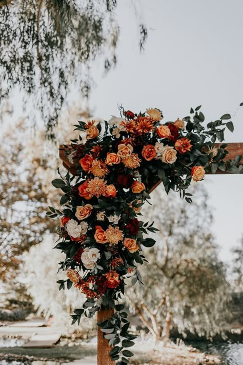 Flowers in different shades of burnt orange and blush decorate the cornor of a wooden arbor at Galway Downs in Temecula, CA. Rust Orange And Blush Pink Wedding, Trellis Ideas Wedding, Burnt Orange Weddings Flowers, Burgundy Burnt Orange And Gold Wedding, Blush And Burnt Orange Wedding, Maroon Burnt Orange Wedding, Rust And Burgundy Wedding Decor, Burnt Orange Wedding Florals, Burnt Orange Wedding Aisle