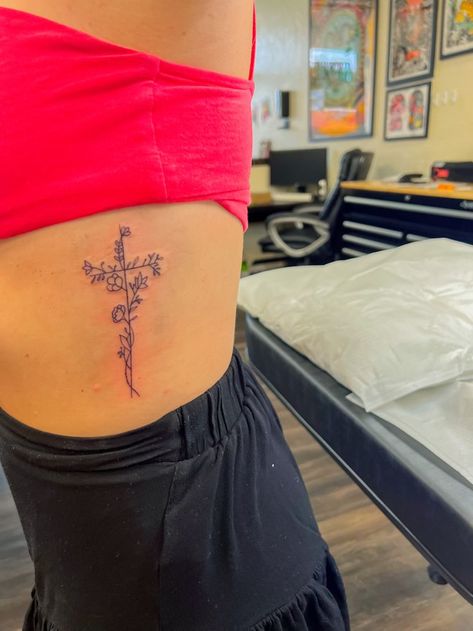 Flower With Faith Stem Tattoo, Cross With Flowers And Butterflies Tattoo, Dainty Cross With Flowers Tattoo, Cross On Side Ribs, Flower Cross Spine Tattoo, Flower Cross Rib Tattoo, Cute God Tattoos, Cute Medium Tattoos For Women, Cross With Wildflowers Tattoo