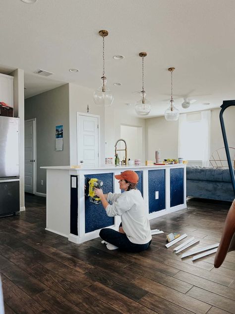 Woman attaching trim to a blue kitchen island Navy Blue Kitchen Island, Kitchen Island Materials, Island Makeover, Kitchen Island Makeover, Blue Kitchen Island, Navy Blue Kitchen, Picture Molding, Home Coffee Stations, Blue Kitchen