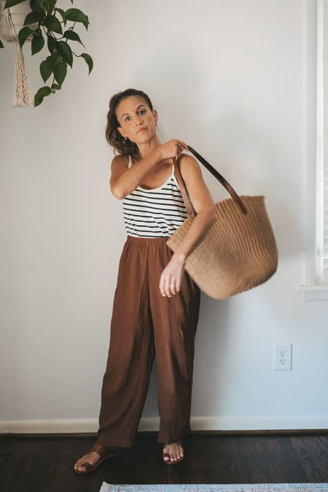 ashley wearing a white and navy striped top, brown drapey pants, brown leather sandals, a tan woven tote bag, and tan frame sunglasses Natural Style Outfits Women, Natural Women Style, Linen Office Outfit, Elevated Granola Style, Casual Outfits Florida, Cottage Outfit Summer Casual, Natural Fiber Clothing For Women, Rust Linen Pants Outfit, Sydney Outfits Summer