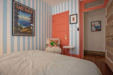 Coral painted trim in striped wallpapered guest bedroom. Stripped Walls Ideas, Striped Accent Wall Bedroom, Vertical Stripes On Wall, Blue And White Striped Wall, Striped Bedroom Walls, Vertical Painted Wall Stripes, Multi Colored Striped Wall, Simple Guest Bedroom, Striped Walls Bedroom