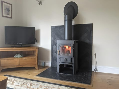 Slate Tile Wood Stove Surround, Tiling Behind Log Burner, Wood Stove Surround Corner, Corner Wood Burning Stove, Stove Corner Ideas, Wood Stove Heat Shield, Earthy House, Herringbone Fireplace, Wood Stove Surround