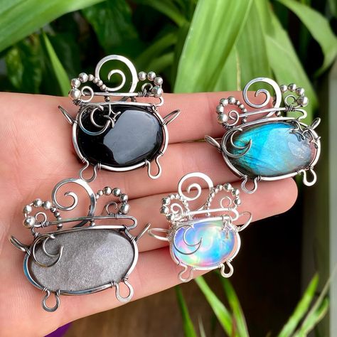 Which one is your favorite? 💜 It’s that time of the year again! These four cauldron necklaces will be in shop this Friday the 13th! ✨ Set your alarms for 1pm EST this Friday! Shop link 👉 www.abbeyroadcollection . .. . #cauldron #witchyjewelry #wirewrappedjewelry #wirewrap #jewelry #crystaljewelry #crystalnecklace #wirewrapsofig #crystaljewellery #handmadejewelry #silverjewelry #statementjewelry #ooakjewelry #jotd #instajewelry #jewelryaddict #halloween #holidayshopping #halloweenjewelry #g... Wire Wrapped Cauldron Tutorial, Wire Wrapped Cauldron, Spooky Wire Wrap, Spiritual Crescent Wire Wrapped Necklaces, Wire Wrapped Cauldron Pendant, Wirewrap Jewelry, Wire Wrapped Moon, Spiritual Wire-wrapped Metal Crystal Necklace, Moon Ring