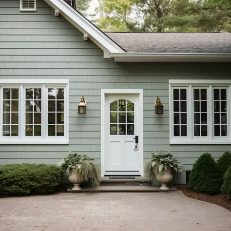 sage green home exterior with a white front door Sage Green Outside House Paint, Green Paint Outside House, Woodland Sage Behr Paint Exterior, House Colors Outside Paint, Sage Green Homes Exterior, Green And White Cottage Exterior, Popular Green Exterior Paint Colors, Light Sage Green Exterior House Colors, Light Sage Green House Exterior