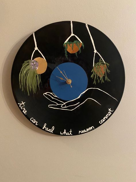 An old record repurposed into a clock with a painted hand hanging plants and “time can heal what reason cannot” quote. Vinyl Clock Diy, Clock Painting Ideas, Painted Vinyl Records, Vinyl Art Paint, Record Painting, Book Cases, Vinyl Record Clock, Clock Painting, Painted Vinyl