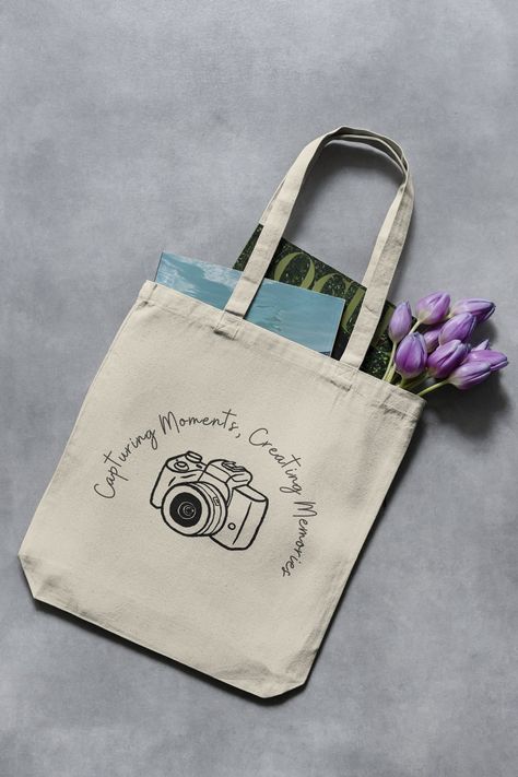 "Elevate the journey of every snapshot with our \"Capturing Moments, Creating Memories\" photography-themed tote bag. Crafted from durable cotton canvas, this stylish carrier is a must-have for shutterbugs who capture life's moments one frame at a time. Perfect for carrying essential photography gear or daily essentials, this tote bag blends functionality with a touch of artistry. Gift the photographer in your life a chic and meaningful accessory that echoes their passion for storytelling throug Totebag Photography Ideas, Canvas Bag Photography, Tote Bags Photography, Tote Bag Product Photography, Tote Bag Photography Ideas, Tote Bag Photoshoot, Bag Photography Ideas, Tote Bag Photography, Creative Tote Bag