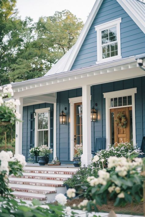 I love using blue paint for home exteriors because it has a versatile and refreshing appeal. The color blue offers a wide range of shades, from soft pastels to bold, vibrant hues, allowing for a diverse array of design options. Whether it's a light, sky blue for a cottage-style home or a dark, moody navy for a modern look, blue paint can be tailored to suit a variety of architectural styles and personal preferences. Natural Shingle House Exterior, Blue Farmhouse Exterior White Trim, Small Blue House Exterior, Chic Exterior House Colors, Blue And Grey House Exterior, Blue Roof White House, Cottage Colors Exterior Colour Schemes, Best Farmhouse Exterior Paint Colors, 1920 Home Exterior