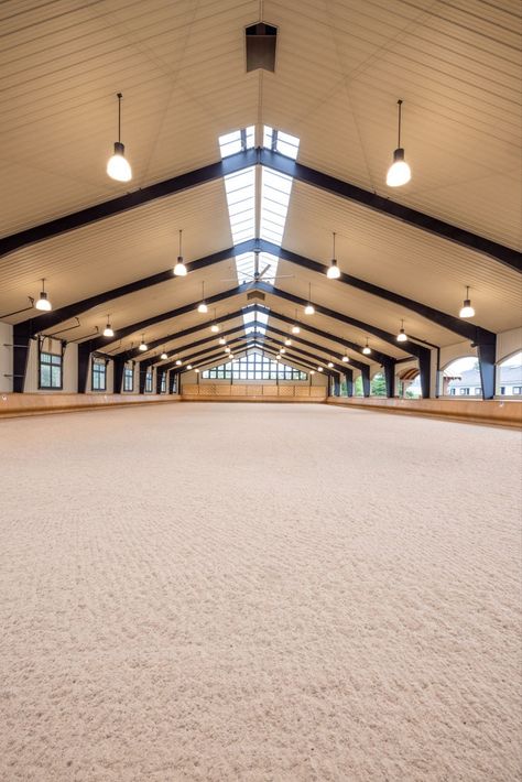 When creating this riding arena, we considered air flow, lighting, materials, the safety of horse and rider, and ease of access to the facility. With arched open-air windows on one side, and large fans overhead, air flow is never a problem. In fact, “garage doors” can be opened on the opposite length of the arena to make it a pavilion setting for maximum breeze. Large windows and skylights bring in plenty of light, while hand-bent wood bumpers keep horses safely away from the outside walls. Equestrian Facility Layout, Minecraft Horse Barn, Horse Barn Layout, Horse Stables Design, Equine Stables, Dream Barn Stables, Horse Riding Arena, Equestrian Stables, Equestrian Barns