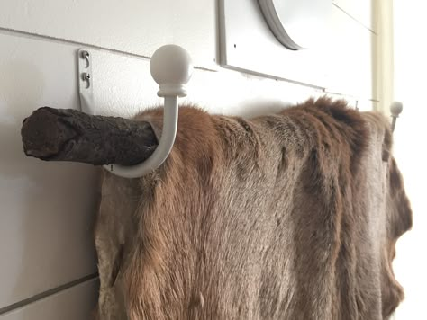 Inexpensive way to hang a deer hide! Get two curtain tie back hooks, and one tree branch. Screw them evenly on the wall. Place the branch across. Drape the hide over carefully and enjoy! Elk Hide Decor, Animal Hide Decor, Bear Skin Rug, Tie Back Hooks, Trophy Display, Curtain Tie Back Hooks, Deer Mounts, Deer Hide, Hunting Decor