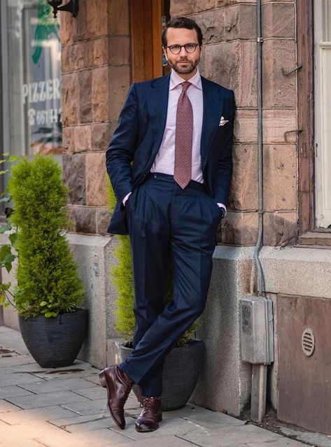 The outfit features a classic navy suit with a pink shirt, burgundy foulard tie with subtle detailing, and burgundy dress boots. Pink Dress Shirt Outfit, Navy Suit Pink Shirt, Classy Pink Dress, Suit Color Combinations, Dress Shirt Outfit, Interview Suits, Navy Suits, Dress Leather Boots, Dress Pants Outfits