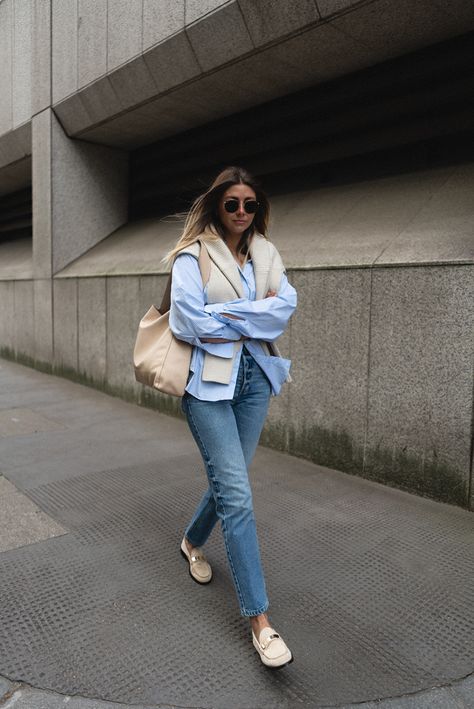 Emma Hill wears blue striped shirt, beige ribbed jumper over shoulders, mid wash straight leg jeans, beige suede loafers. Spring outfit Vionic Loafers Outfit, Beige Loafers Outfit Women, Beige Loafers Outfit, Loafer Outfits Women, Loafers Outfit Women, London Wardrobe, Blue Striped Shirt Outfit, Spring Uniform, Loafers Outfits