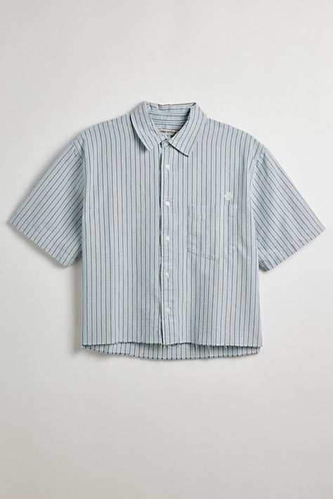 Updated stripe pattern Oxford shirt with a cropped hem. Short sleeve button-down shirt with a standard collar and left chest pocket. Features UO striped cut-off Oxford shirt Short sleeve shirt Standard collar Button-down front Chest pocket Boxy silhouette Cropped hem Content + Care 100% Cotton Machine wash Imported Size + Fit Model in Blue + Grey Stripe 6’2" and wearing size Medium Measurements taken from size Medium Chest: 24" Length: 23.5" | Urban Outfitters UO Striped Cut-Off Oxford Shirt Top T Shirts Streetwear, Striped Button Up, Cropped Button Up, Men Wishlist, Cropped Shirt Men, Pastel Mens Fashion, Button Up Shirt Men Outfits, Short Sleeve Button Up Men, Dress Shirts Men