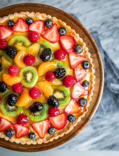 An overhead shot of fresh fruit tart on a wooden stand. Fruit Tart Breakfast, Classic Fruit Tart, La Madeleine Fruit Tart Recipe, Fruit Torte Cake, Custard Fruit Tart Recipe, Homemade Fruit Tart, Whole Foods Fruit Tart Recipe, Best Fruit Tart Recipe, Fruit Tart Pie