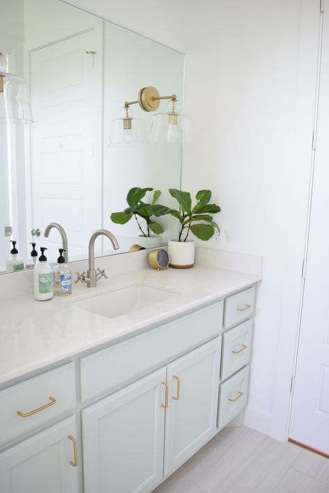 Bright and airy bathroom with Sea Salt painted cabinets, brass hardware and light fixtures and polished nickel plumbing. White Cabinets Brass Hardware, Seafoam Cabinets, Powder Blue Bathroom, Brass Hardware Bathroom, Small Bathroom Redo, Sea Salt Paint, Sherwin Williams Sea Salt, Bathroom Cabinet Colors, Sea Salt Sherwin Williams