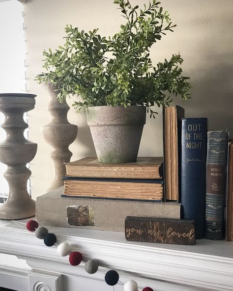 January Mantle with old books, a plant and fuzzy ball garland!   #farmhouse Book Mantle Decor, Mantle Decor With Books, Old Books Decor Display, Mantle With Books, Books On Fireplace Mantle, Books On Mantle, January Mantle, Vintage Mantle Decor, Style Mantle