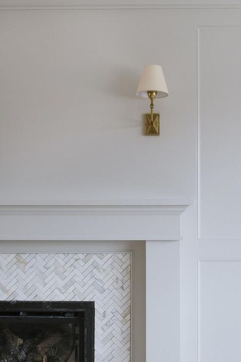 A Jane Wall Sconce is mounted above a white fireplace mantel fixed framing carrera marble herringbone surround tiles. Herringbone Tiles Fireplace, Herringbone Fireplace Surround, Herringbone Tile Fireplace, White Fireplace Mantel, Studio Mcgee Fireplace, Herringbone Fireplace, White Fireplace Mantels, Kitchen Living Rooms, Fire Surrounds