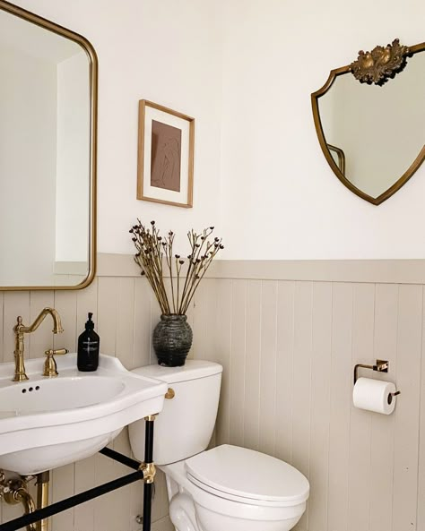 We are loving the warmth in this bathroom! This wainscoting allows the two different colors used in this space and we are loving it! These brass accents like the faucet and the trim around the mirror bring in the vintage charm and the other mirror on the side wall helps open up this space even more! | Signature Hardware #bathroom #vintage #vintagebathroom #wainscoating #brassaccents #warmtones Cottage Bathroom, Casa Vintage, Casa Container, Upstairs Bathrooms, Downstairs Bathroom, Bathroom Renos, Bathroom Inspo, Bathroom Reno, House Bathroom