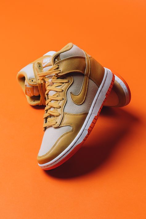 This take on the Dunk High sees the silhouette's classic leather base swapped with a course, tan-coated canvas material. The neutral upper is covered in shades of wheat and gold and create a scheme that's effortless to style, all atop a bright orange outsole that adds some pop underfoot.⁠ Shop now online. Cool Shoe Photography, Basketball Shoe Photography, Nike Shoe Photography, Shoe Photography Ideas, Product Photography Shoes, Shoe Product Photography, Shoes Product Photography, Shoes Photography Ideas, Shoe Reference