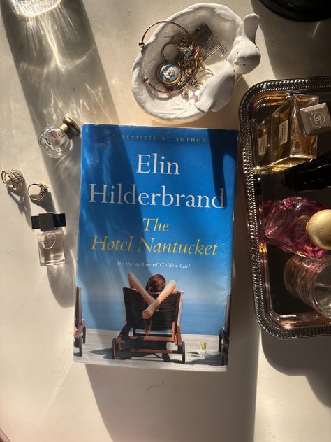 The book Hotel Nantucket next to a bowl of jewelry and perfume The Hotel Nantucket Book, The Hotel Nantucket Book Aesthetic, Hotel Nantucket Book, The Hotel Nantucket, Hotel Nantucket, Elin Hilderbrand Books, Nantucket Hotels, Book Pinterest, Elin Hilderbrand