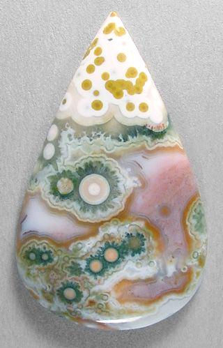 Sam Silverhawk cabochon of ocean jasper, from Madagascar. Ocean jasper never fails to amaze me with its endless variations! This unique cab features a string of small bullseyes and orbs against an attractive aqua agate background Agate Background, Ocean Jasper Jewelry, Crystal Vibes, About Crystals, Green Ocean, Rock Minerals, Pretty Rocks, Crystal Therapy, Beautiful Rocks