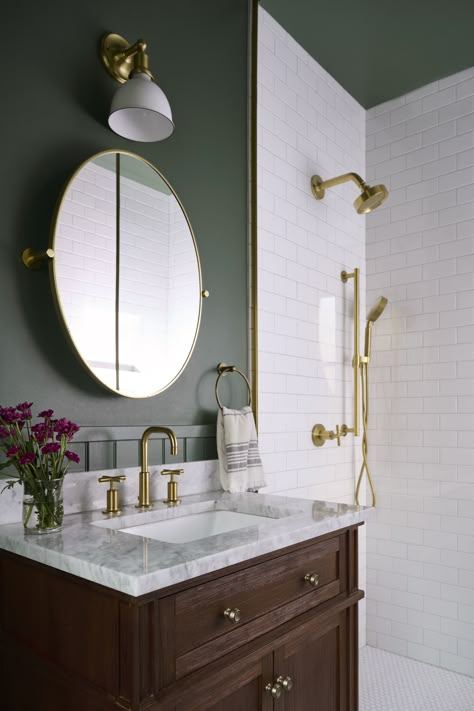 Nothing makes a space feel dynamic and luxe quite like high contrast! In this client's powder bath, we opted for the dark and dreamy Narragansett Green HC-157 by Benjamin Moore for the walls and ceiling. This allows the bright white shower tile to stand out while not dominating the space. Both the Narragansett Green and the white tile provide a beautiful backdrop for the brass pops in lighting and faucets. Bathroom With Dark Ceiling, Bathroom With Dark Green Walls, Bathrooms With Green Vanity, Green Bathroom No Window, Dark Green Powder Bathroom, Green Inspired Bathroom, Green Gold And White Bathroom, Green Bathroom Brass Fixtures, Brass And Green Bathroom