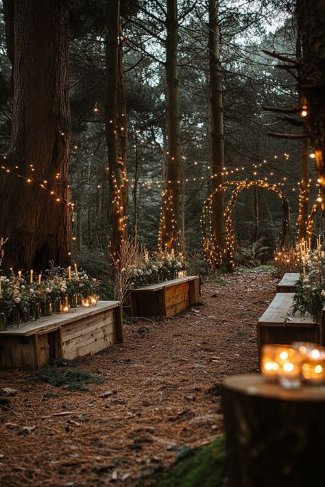 A woodland path is adorned with glowing string lights and lined with wooden benches. The setting is enhanced with flowers and candles, creating a cozy and enchanting atmosphere in a forest. Wooded Backyard Wedding, Forest Wedding Colorado, Solstice Wedding Summer, Forest Wedding Mood Board, Cheap Forest Wedding, Camp Out Wedding, Forest Wedding Table Setting, Gloomy Wedding Aesthetic, Bonfire Wedding Ideas