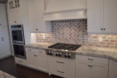 Lovely kitchen features a white wood French range hood situated over a red brick herringbone cooktop backsplash and an integrated gas cooktop over pot and pan drawers next to double ovens. Red Brick Kitchen, White Brick Backsplash, Exposed Brick Kitchen, Brick Kitchen Backsplash, Brick Backsplash Kitchen, White Kitchen Backsplash, White Tile Backsplash, Brick Kitchen, Brick Backsplash